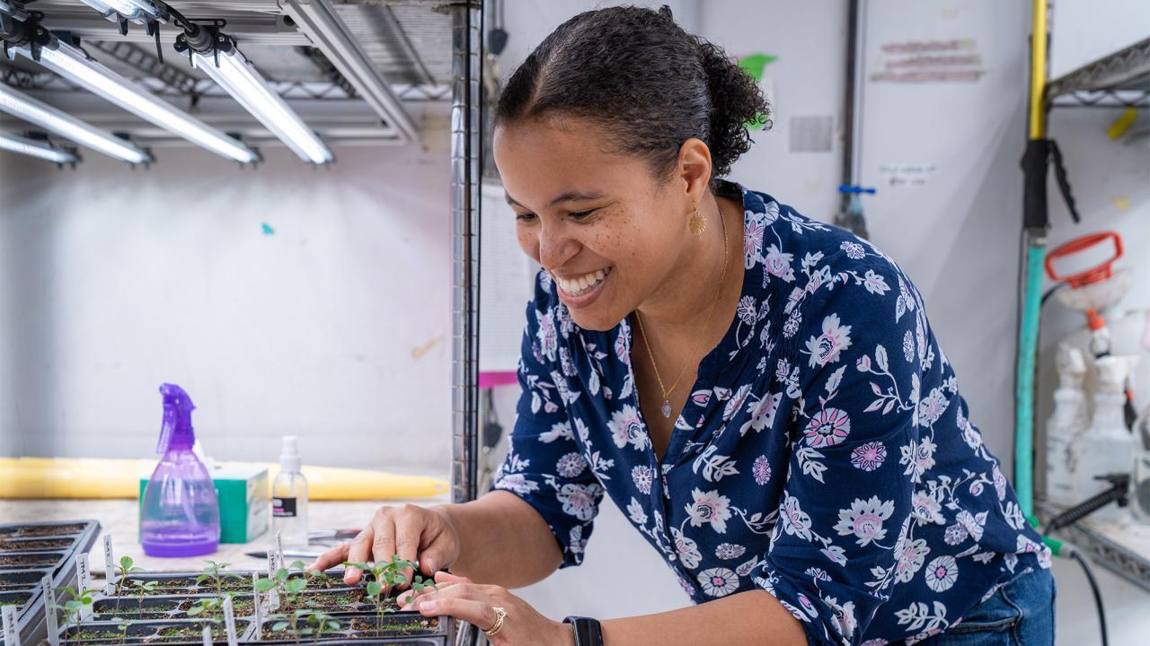 Smiling woman in floral blouse assembling electronics on a workbench in a lab