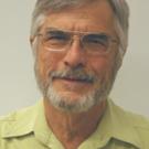 Elderly man with gray beard and glasses, wearing light green shirt, portrait photograph.